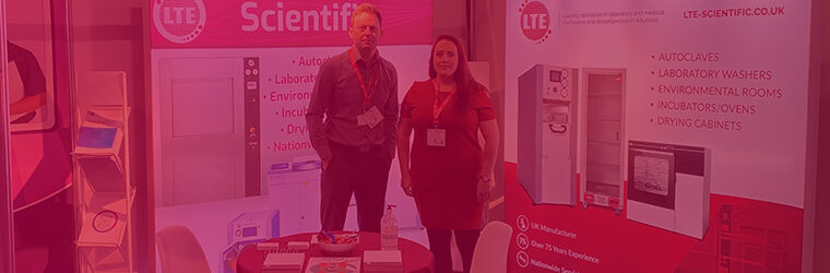 two people stood at exhibition stand with pink 'lab innovations' overlay